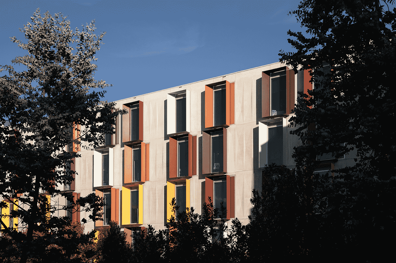 A shot of the side of a student accomodation building with lots of trees around-min