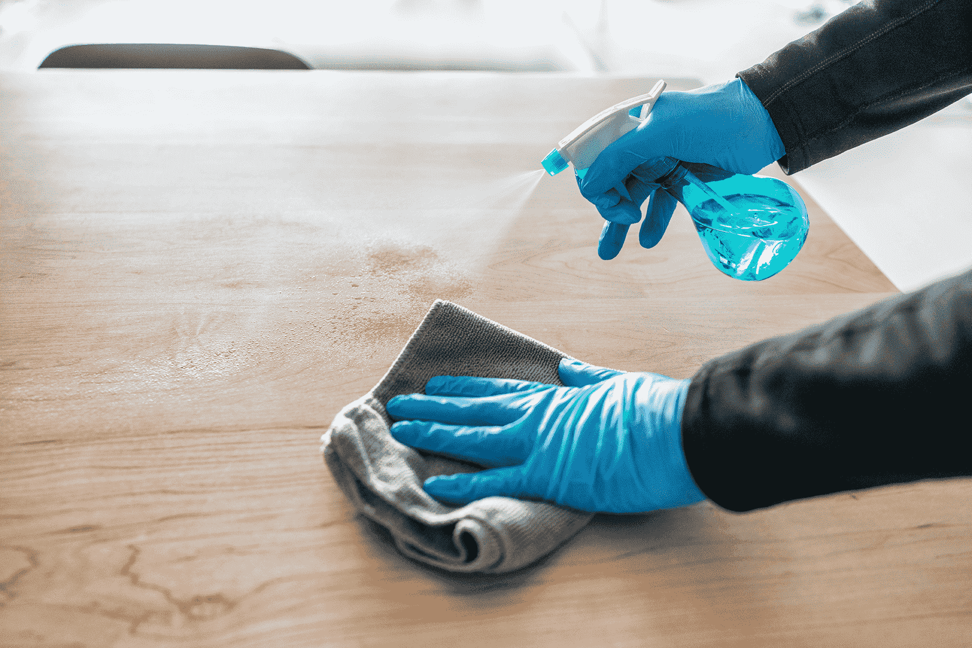 a close up shot of a cleaner wiping a table-min