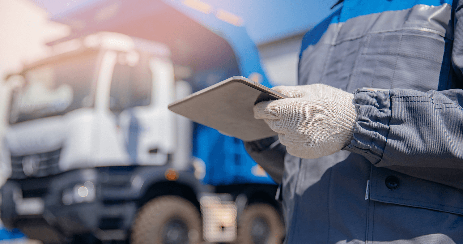 a waste worker uses a tablet to complete a job by his truck