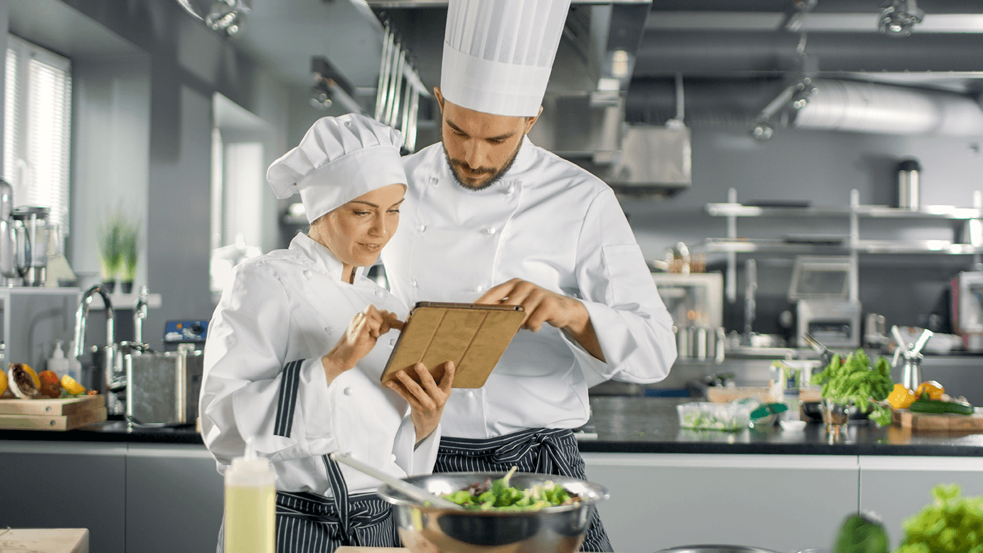 a chef shows a colleague how to complete an audit using his tablet[1]-min